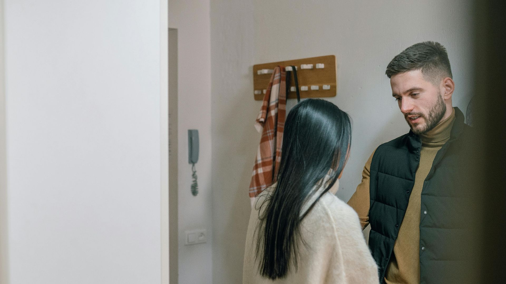 A man and woman talk inside a cozy home. They appear engaged in a conversation.