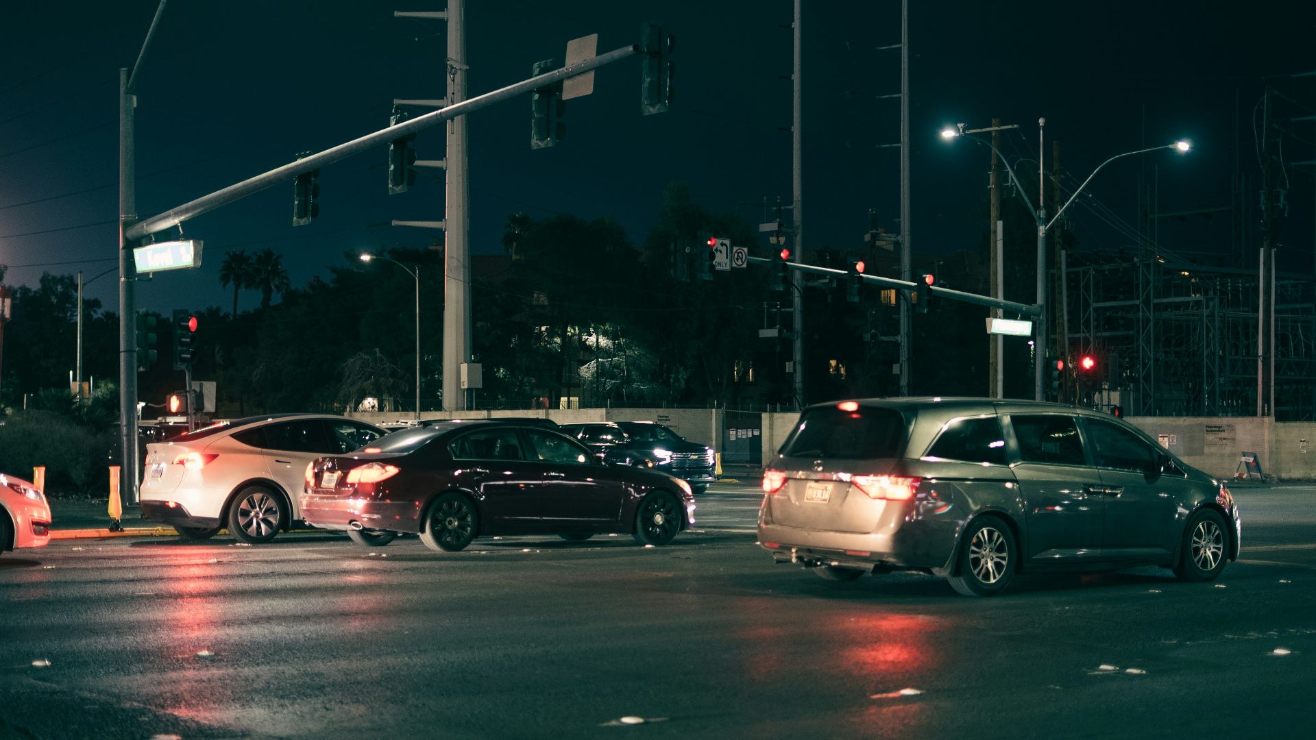 Cars waiting at a traffic light at night.