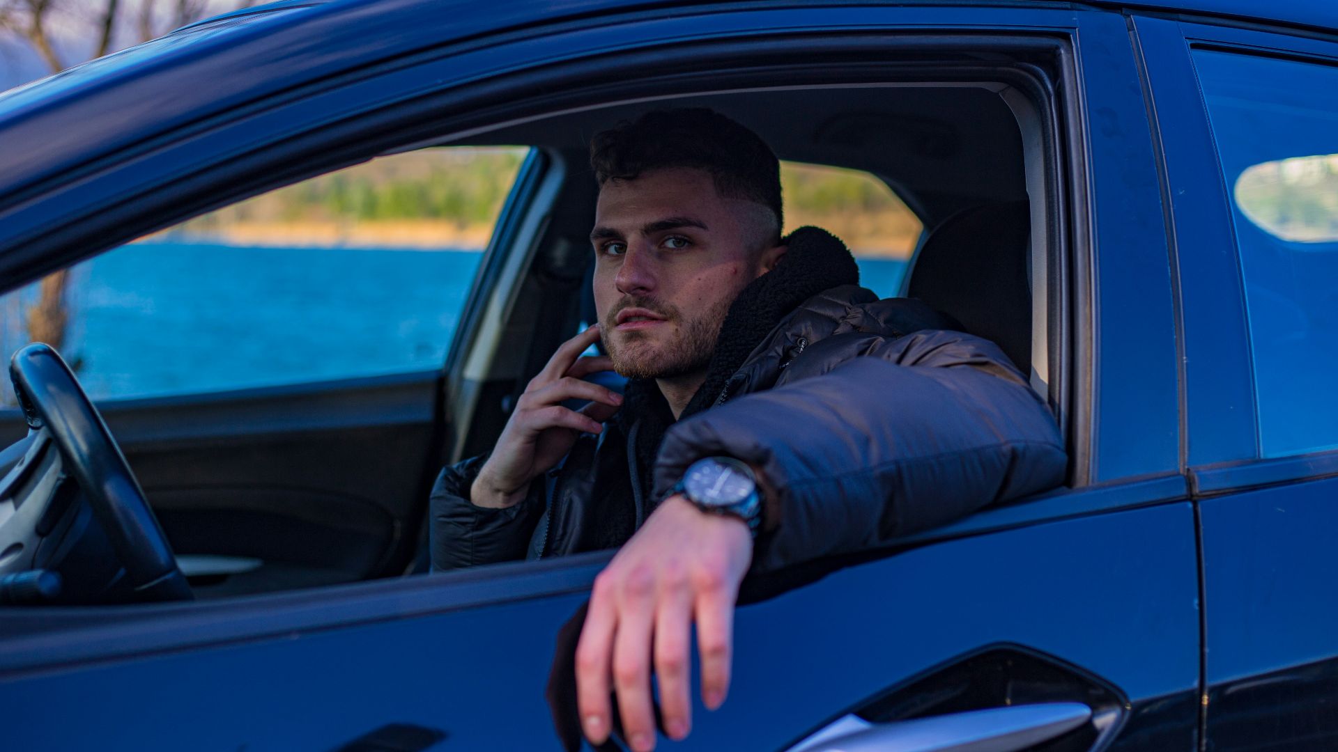 a man sitting in a car talking on a cell phone