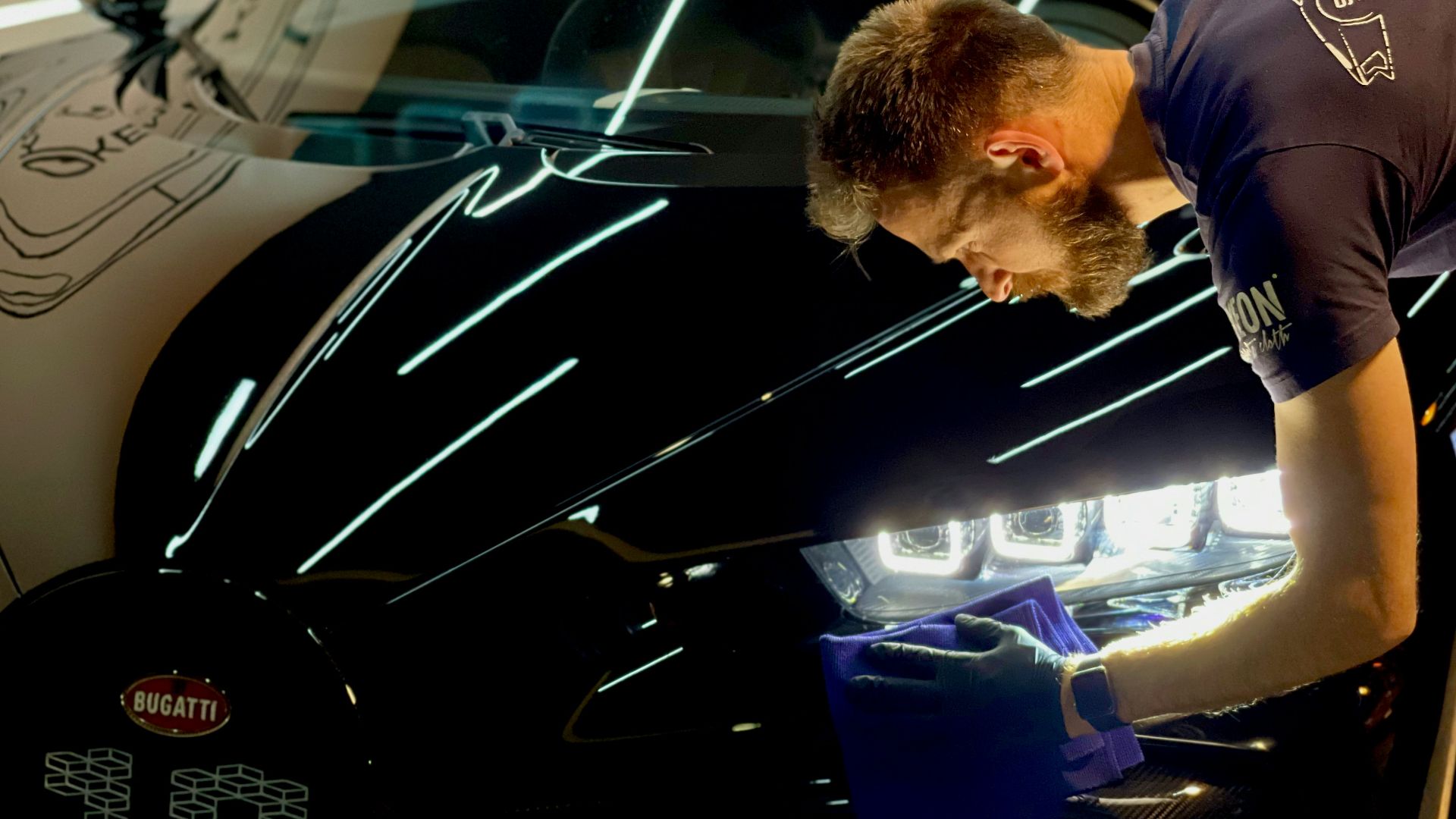 man in blue crew neck t-shirt standing beside black car