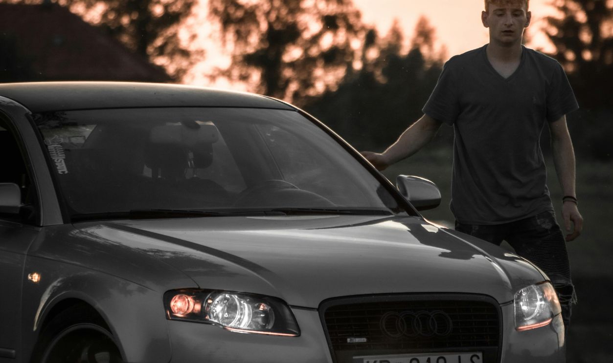 Close-Up Shot of a Man Standing beside a Car during Sunset