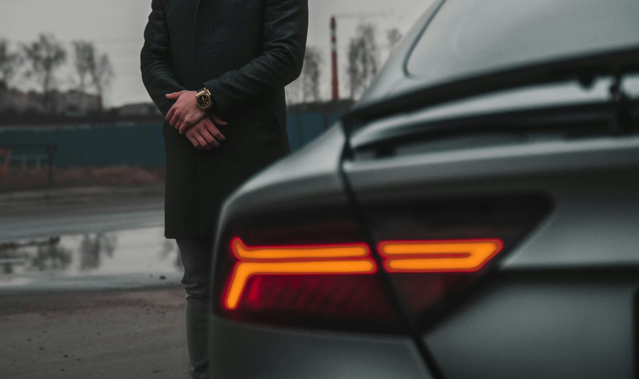 A Man in Black Coat Looking at the Parked Car on the Side of the Street