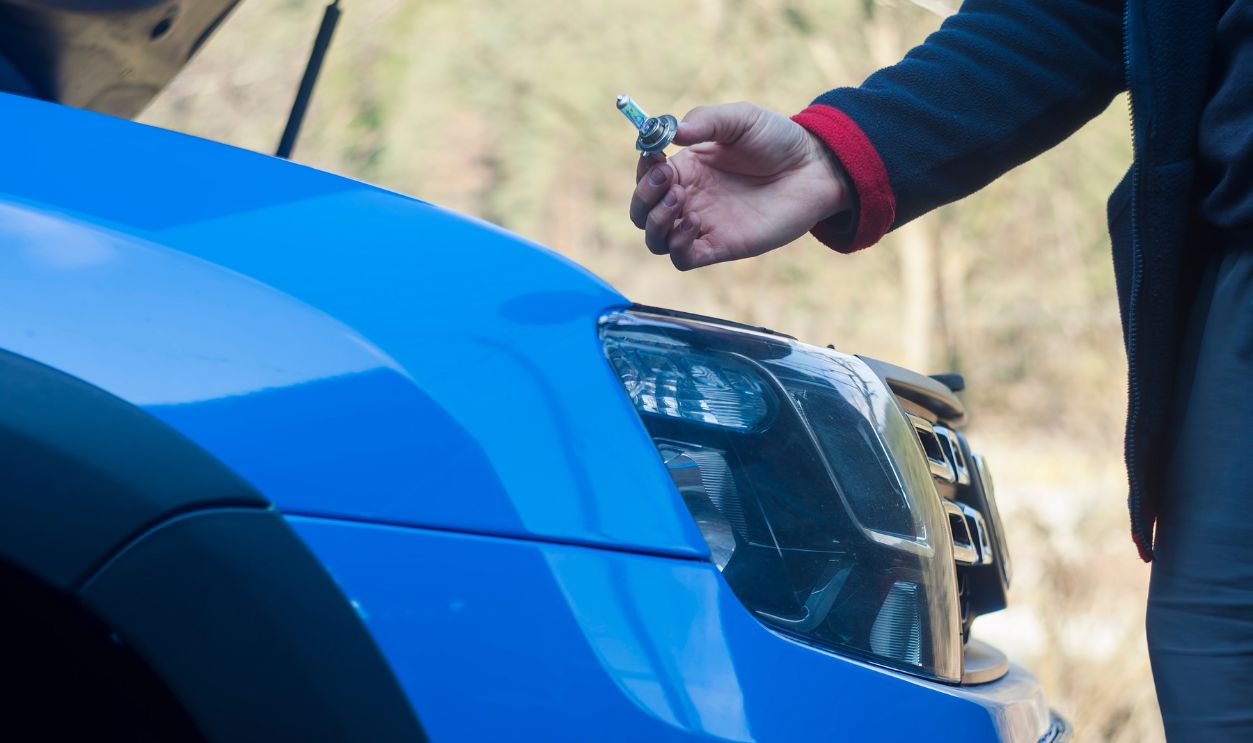 man hand changing light bulb on car headlight