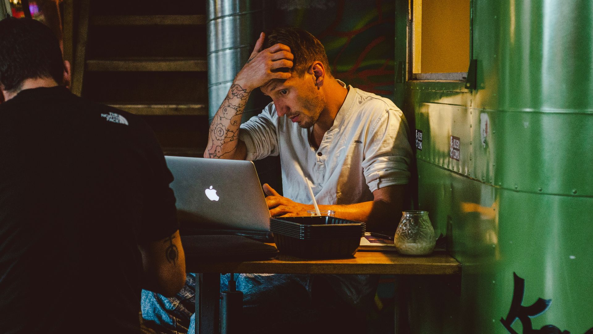 man in front of silver MacBook while scratching his head