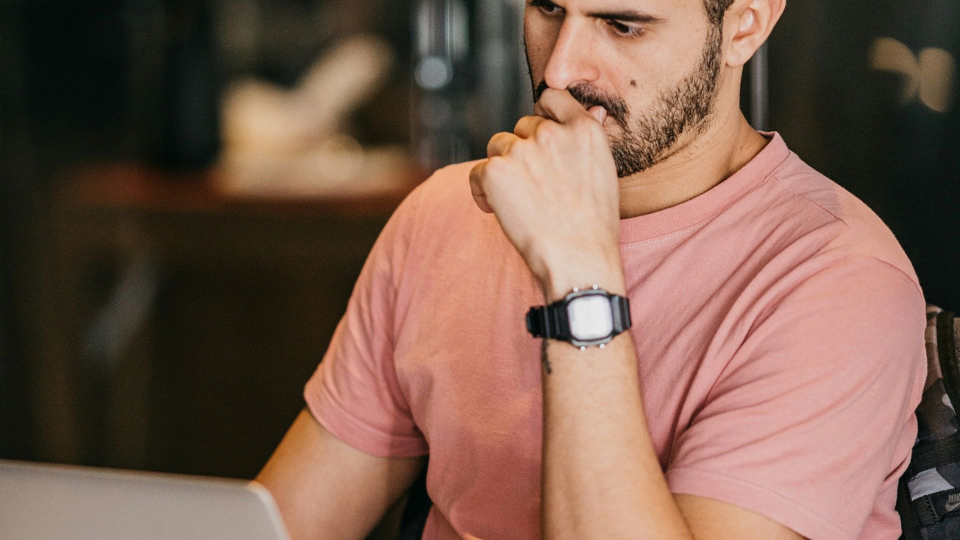 a man sitting at a table with a laptop and a cup