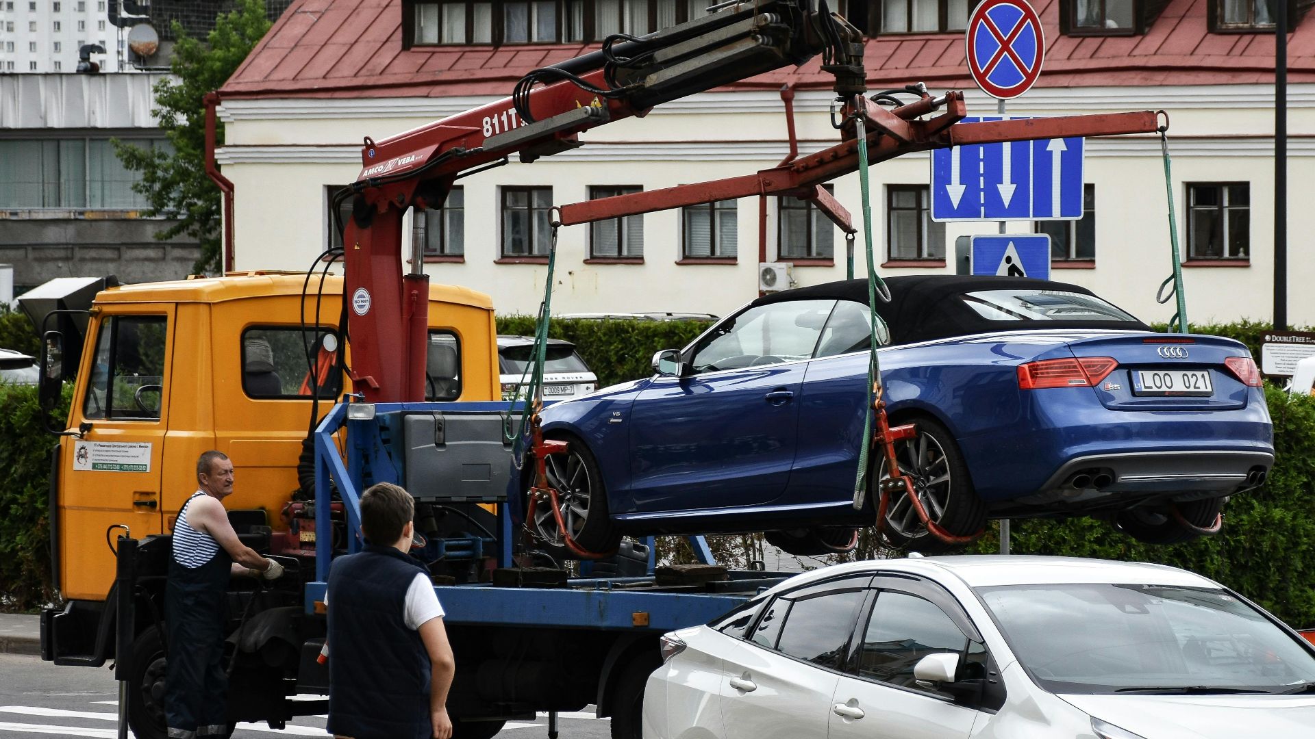Towing a blue Audi convertible in a bustling city street.