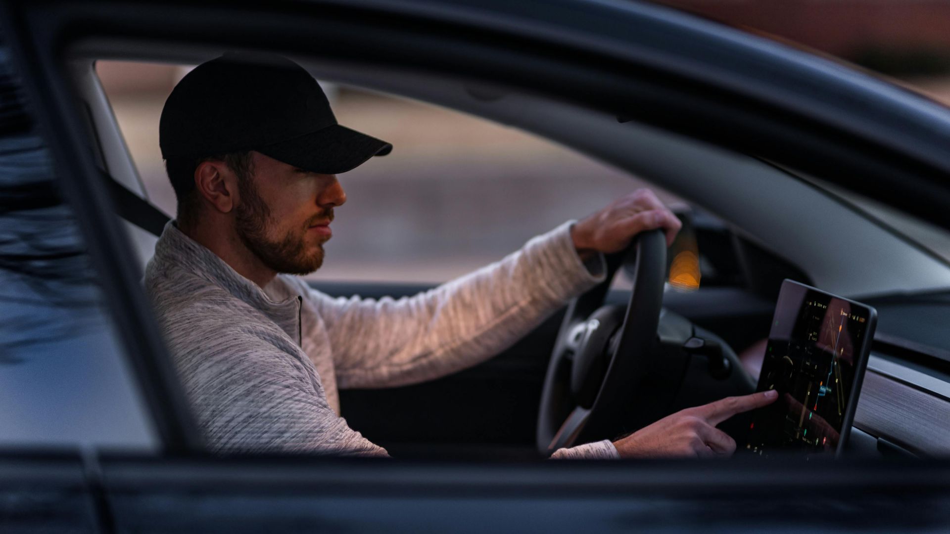 A man interacts with a touchscreen inside an electric car, driving through Dallas, TX.