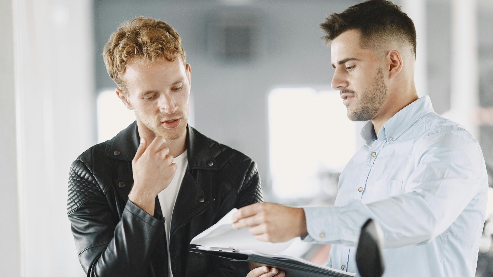 Two adults discussing purchasing options at a motorcycle dealership.