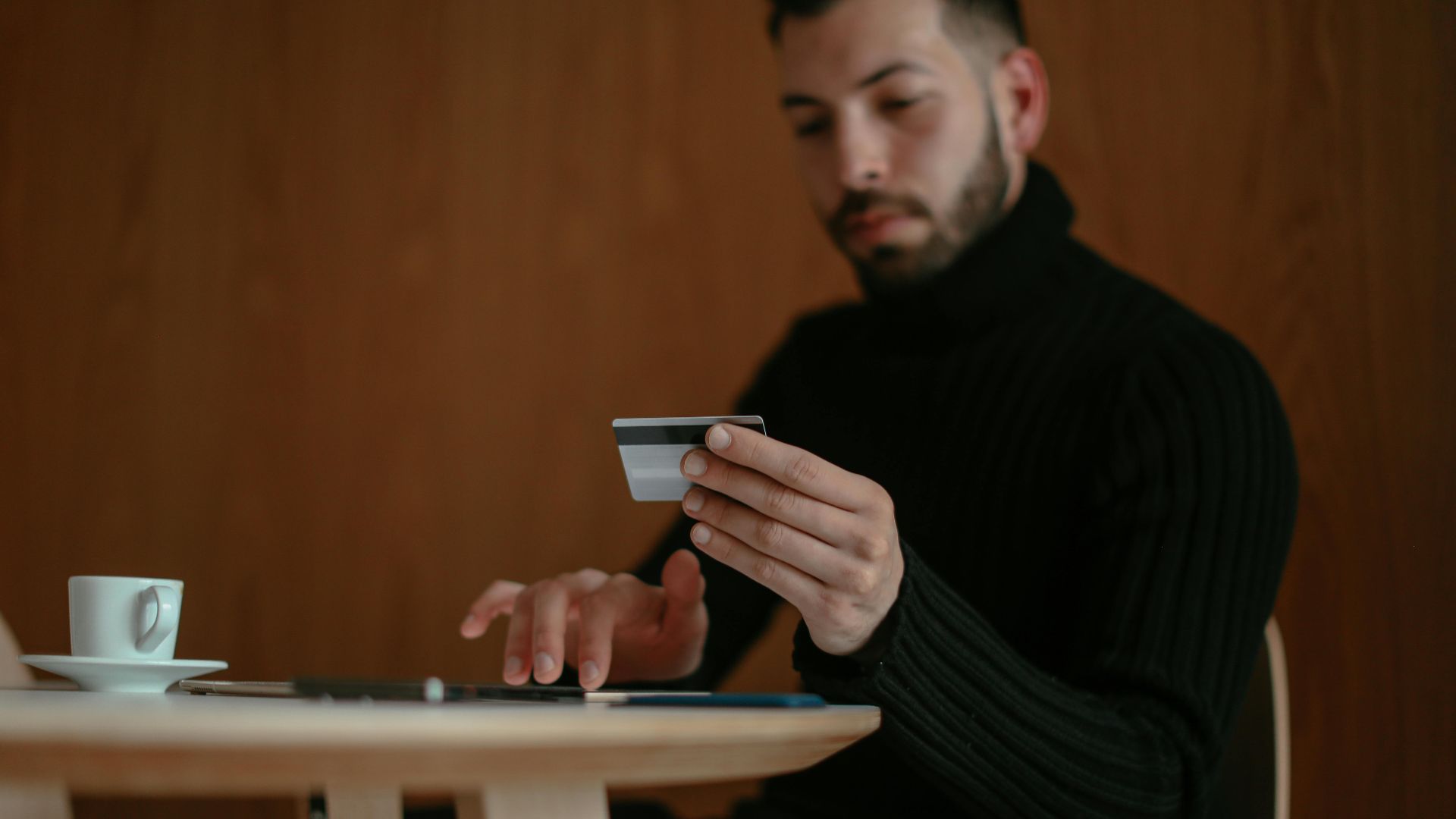 Focused man in café using tablet and credit card for online shopping.