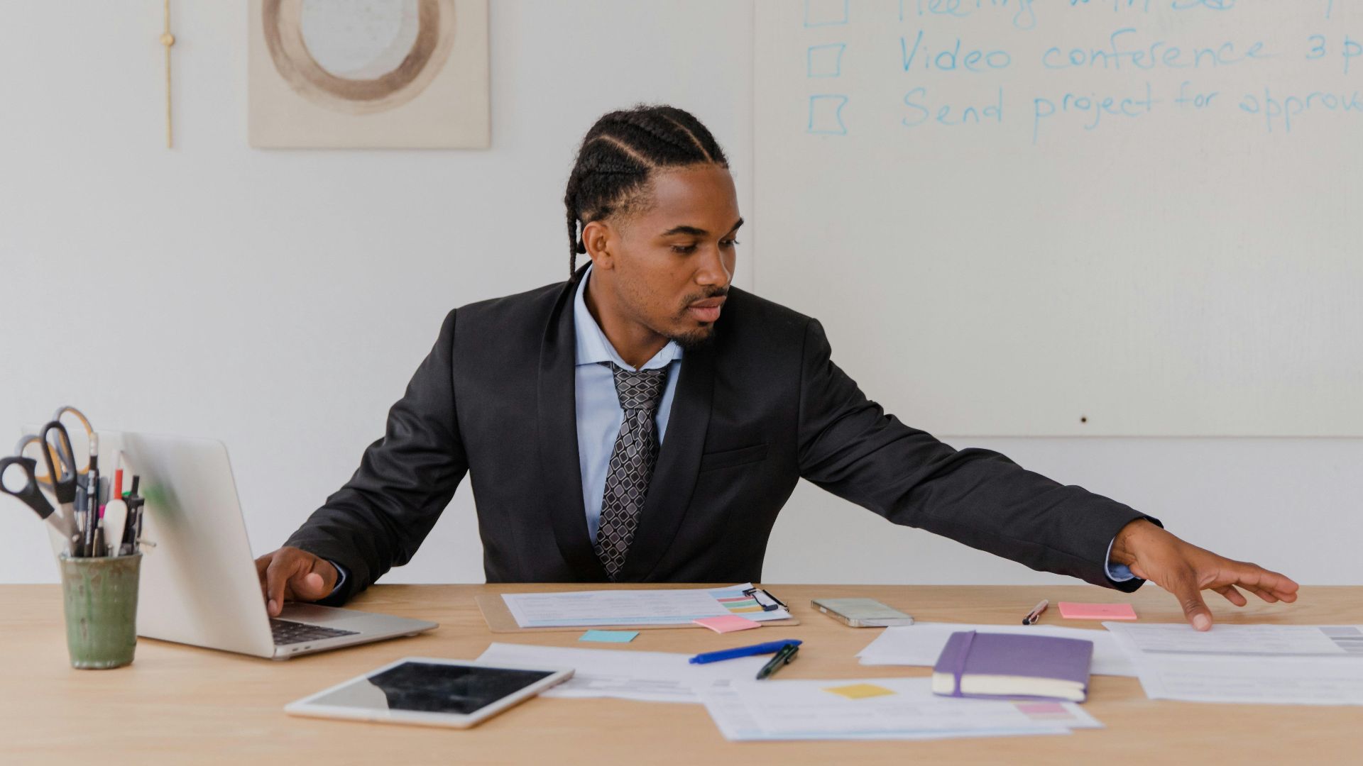 Business professional organizing documents at a desk in a modern office setting.