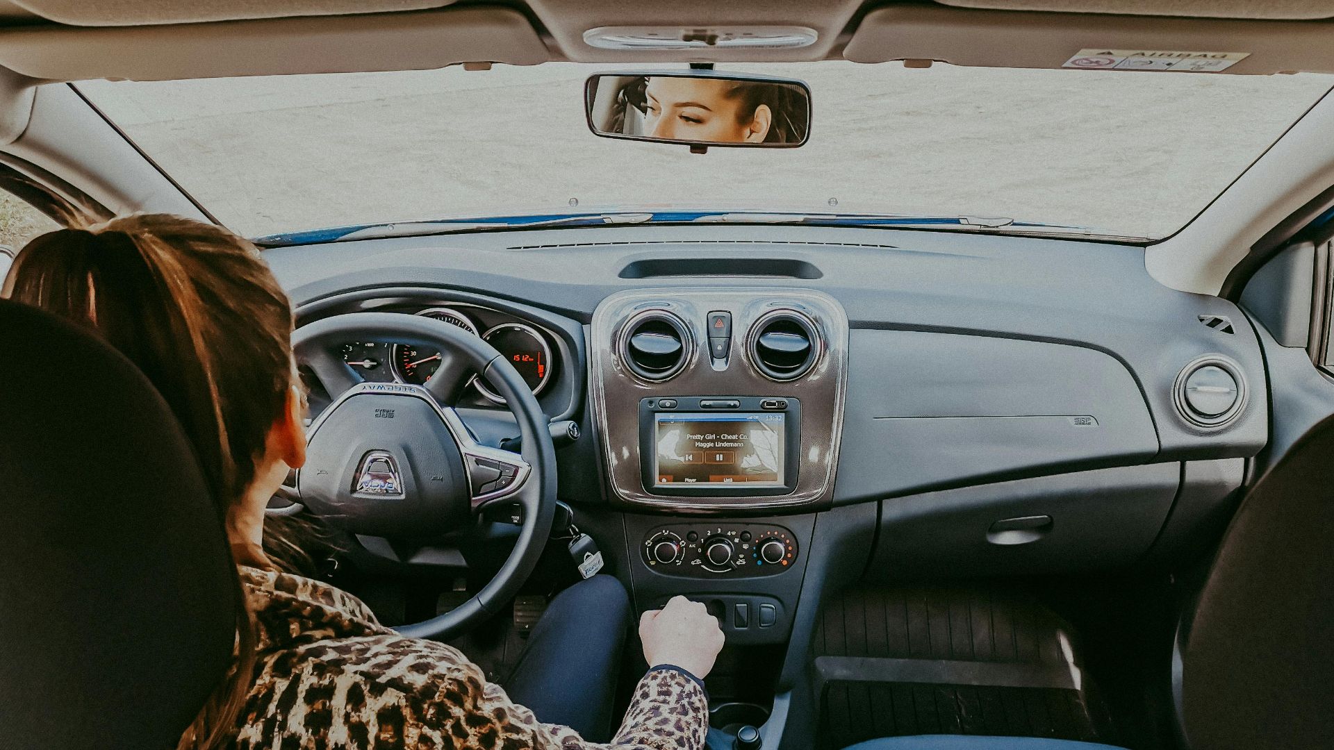 Back view of modern woman in stylish fur coat driving car confidently looking away