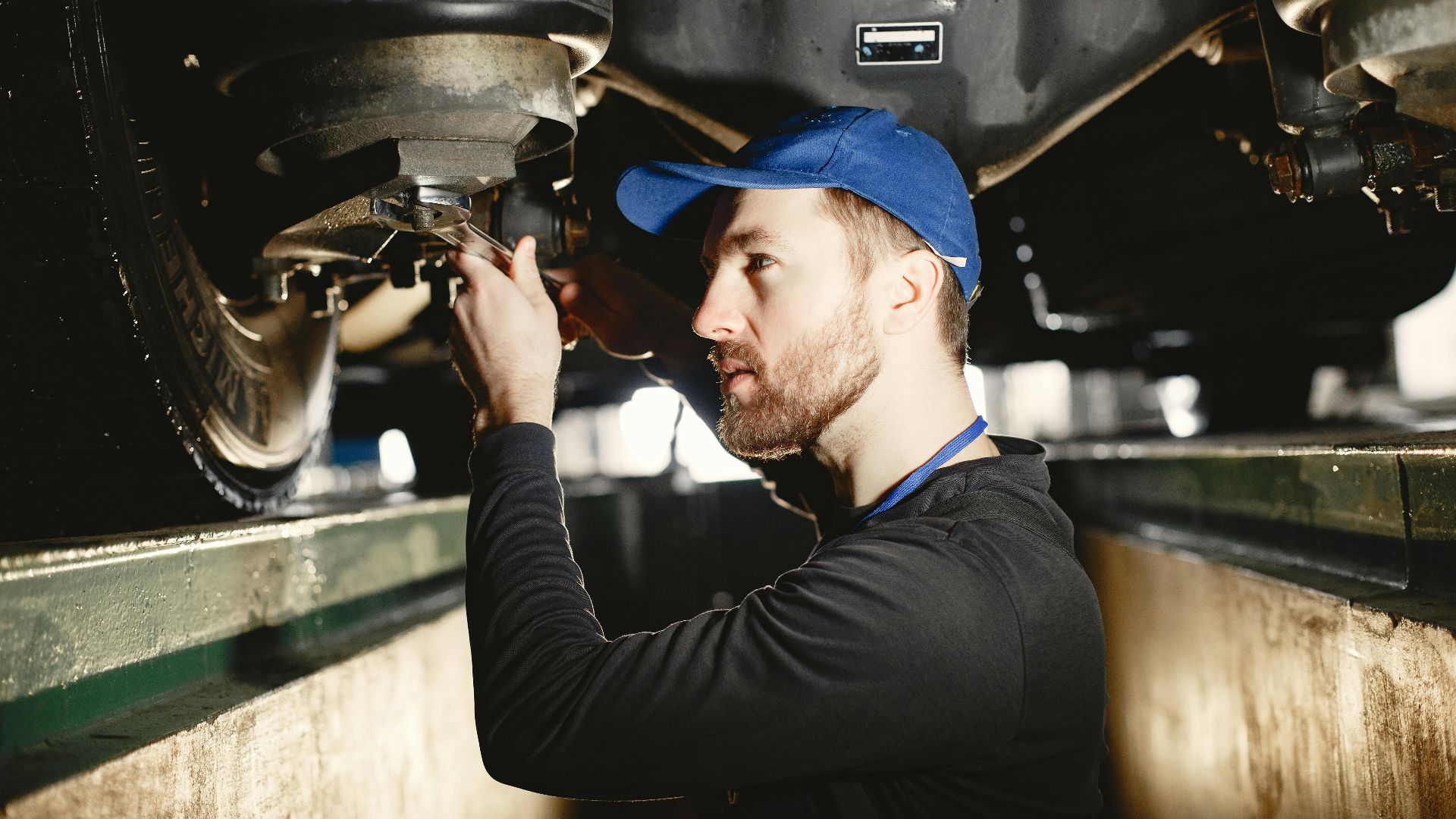 Auto mechanic working diligently on vehicle in workshop setting. Expertise in repair and maintenance.