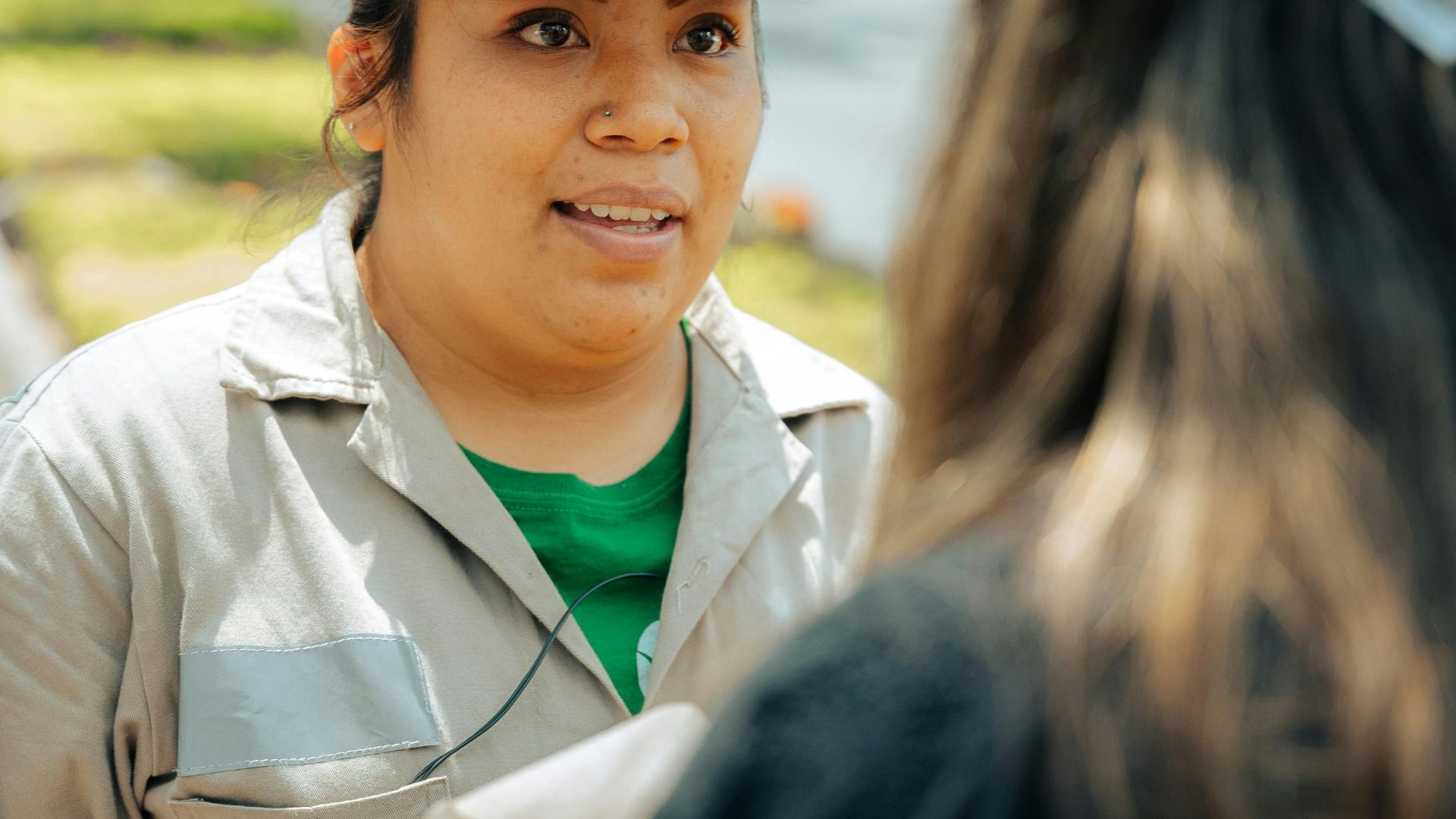 Two women engaged in a conversation on a sunny day in an urban setting.