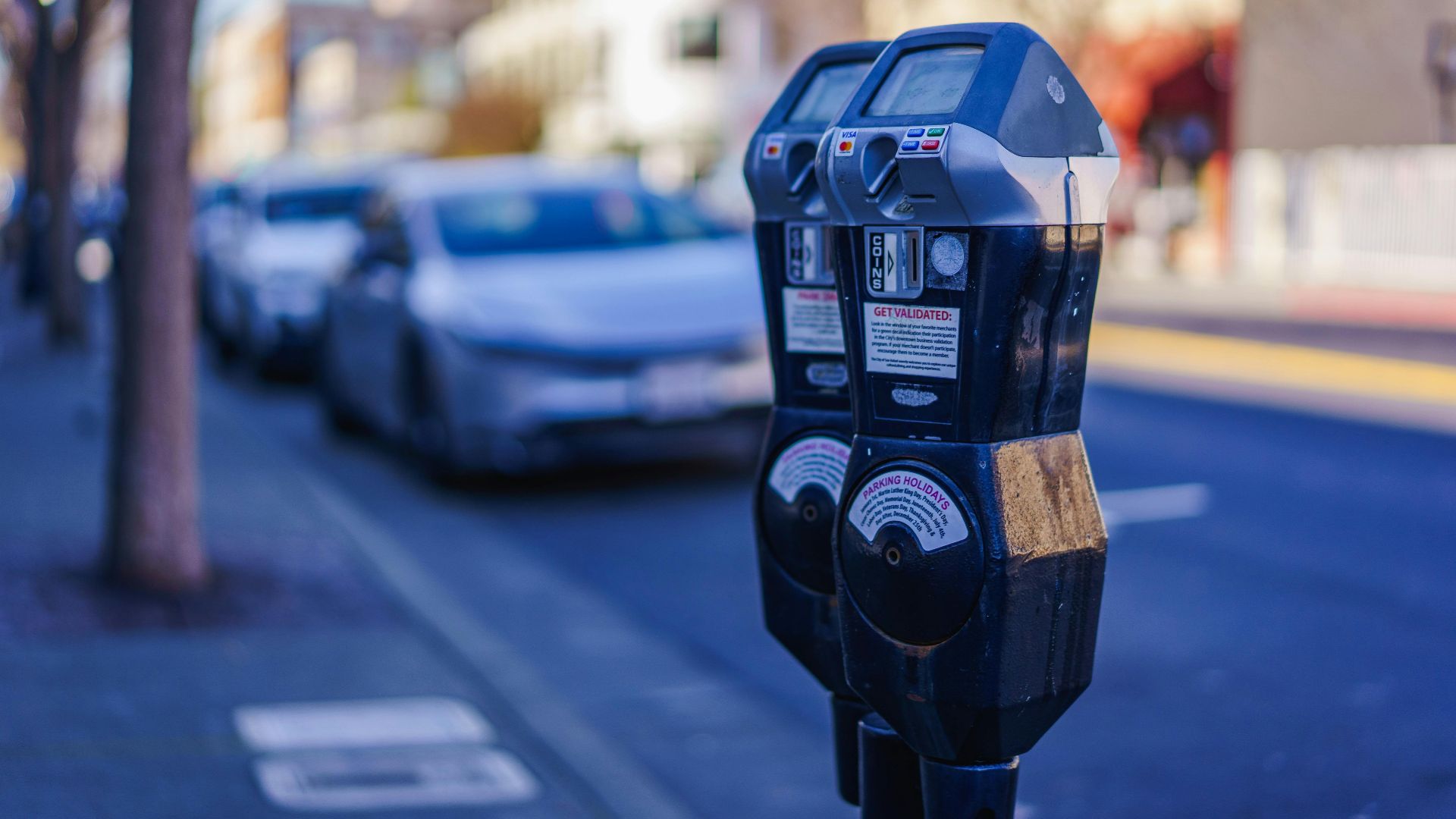 Close-up of parking meters in a bustling city street during the day, showcasing urban infrastructure.