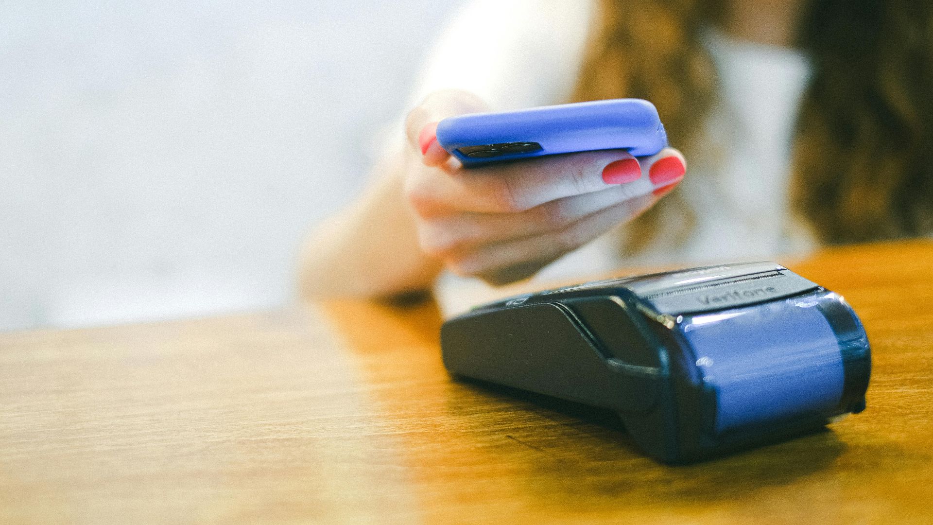 Close-up of a woman making a contactless payment using a smartphone over a card reader