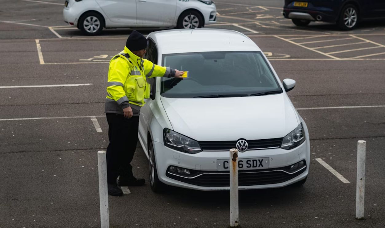 standing near a car with a ticket in hand