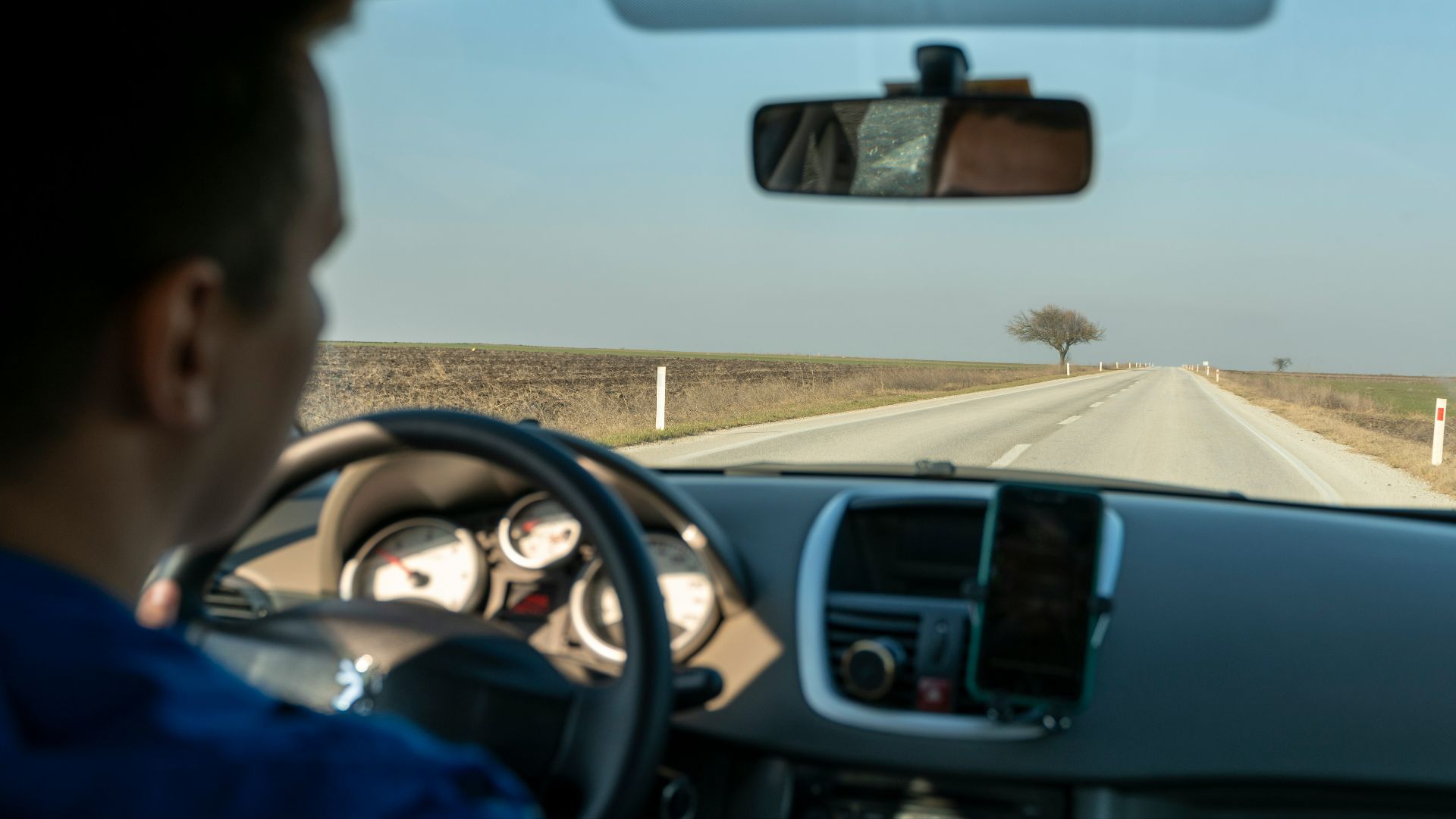 a man driving a car down a country road