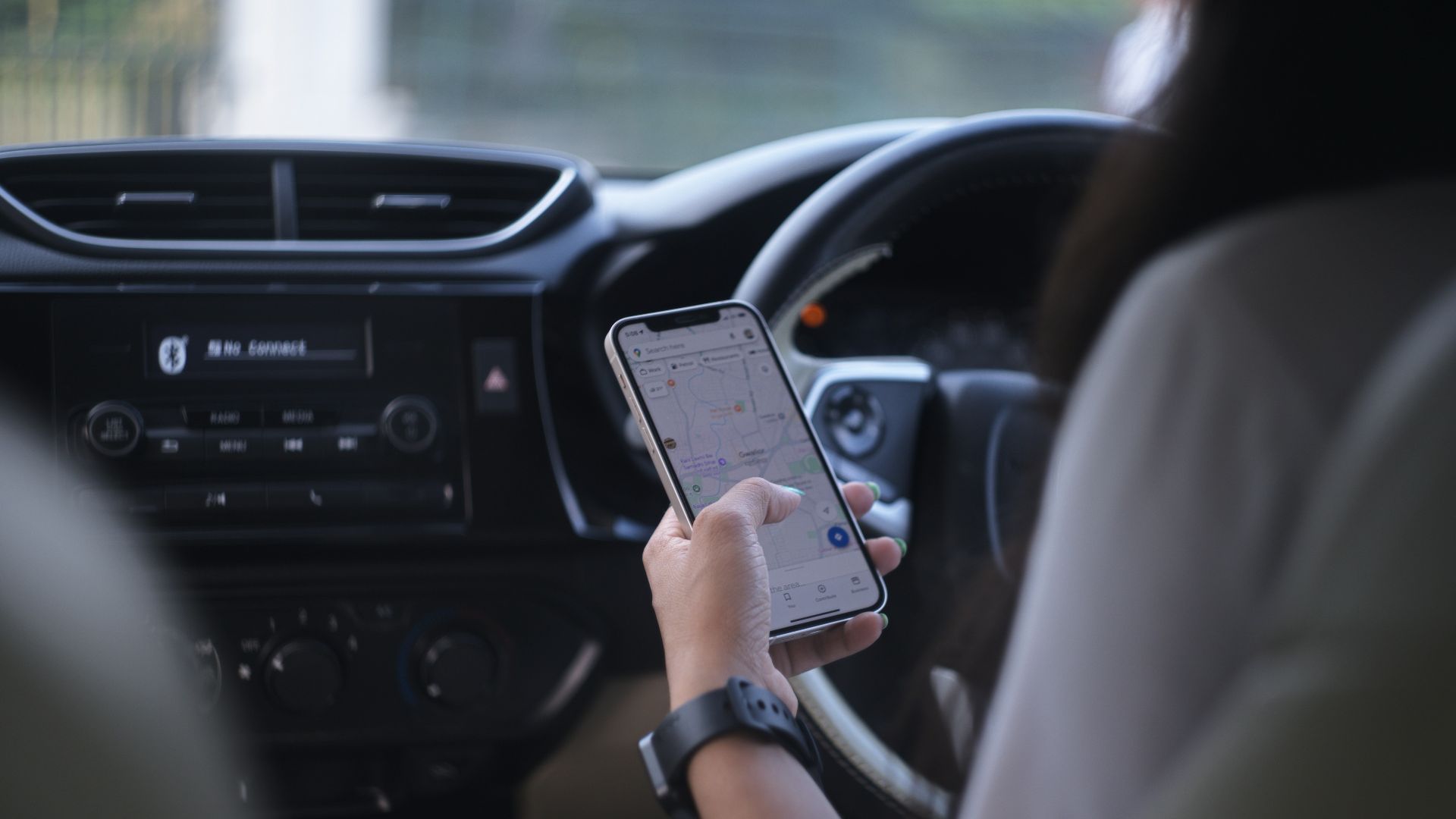 A woman holding a cell phone while driving a car