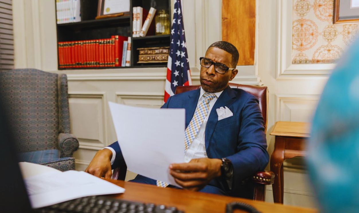 An Attorney in Blue Suit Holding a Document while Sitting