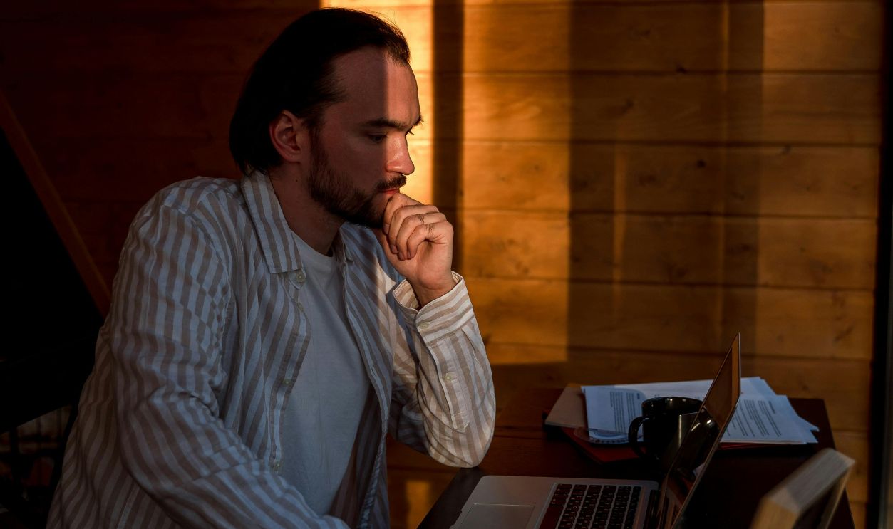 A Man Sitting while Looking at His Laptop