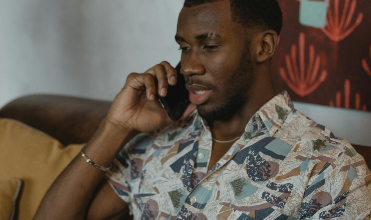 Man in White and Black Button Up Shirt Sitting on Brown Chair
