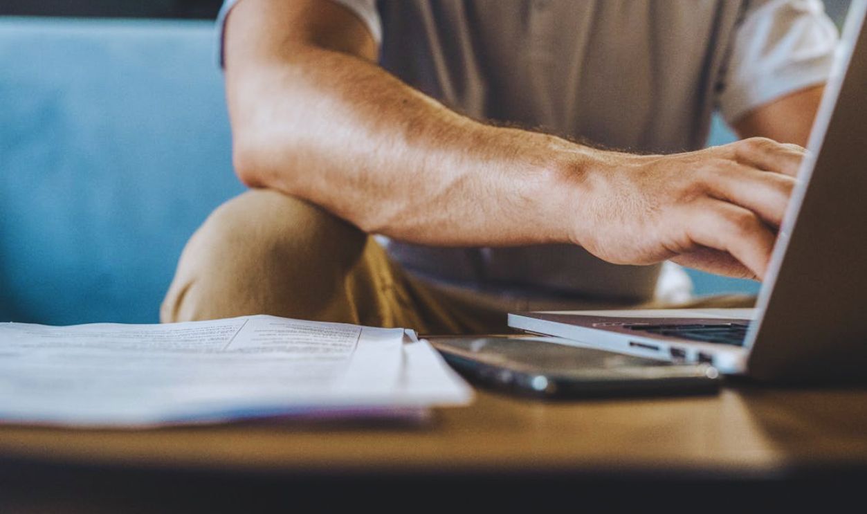 Man in a Gray Shirt Using a Laptop