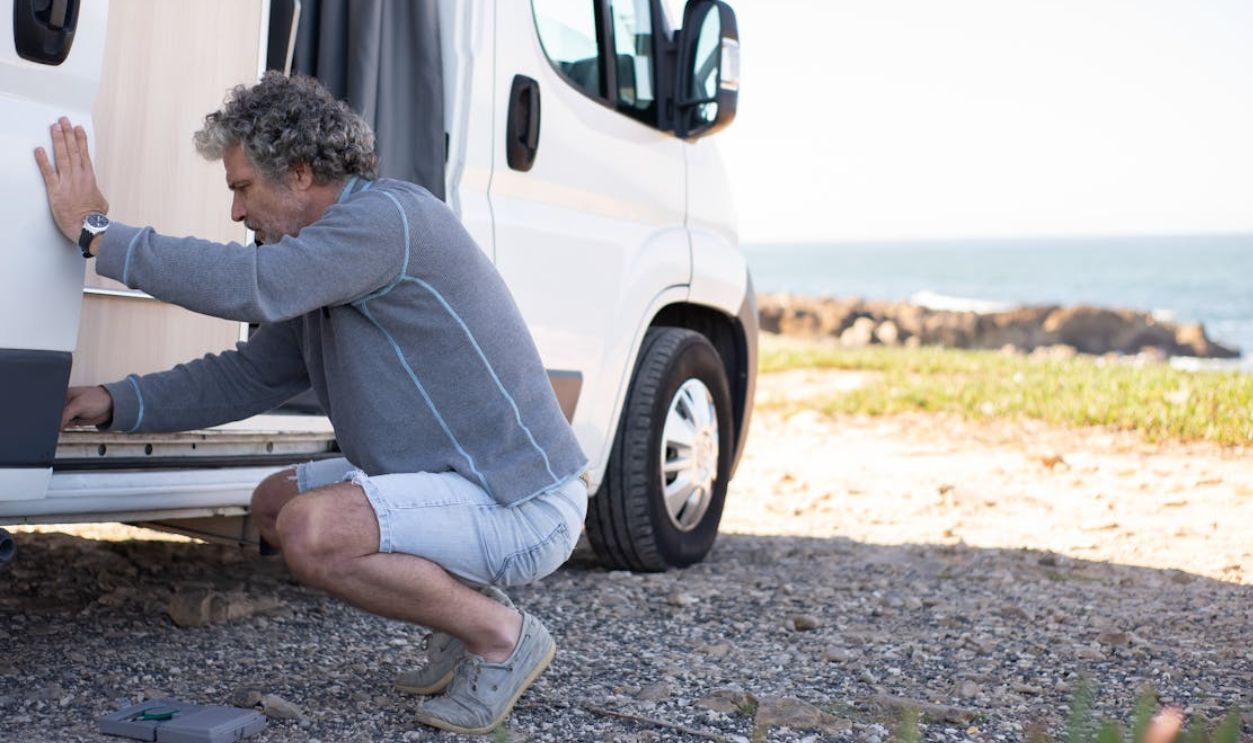 Man Crouching by Caravan