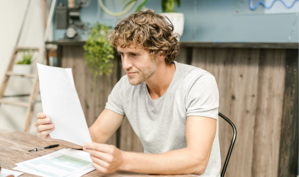 Man in Gray Crew Neck Shirt Reading a Paper