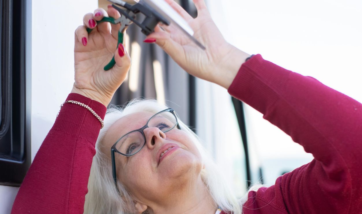 Elderly Woman Fixing a Window in a Campervan