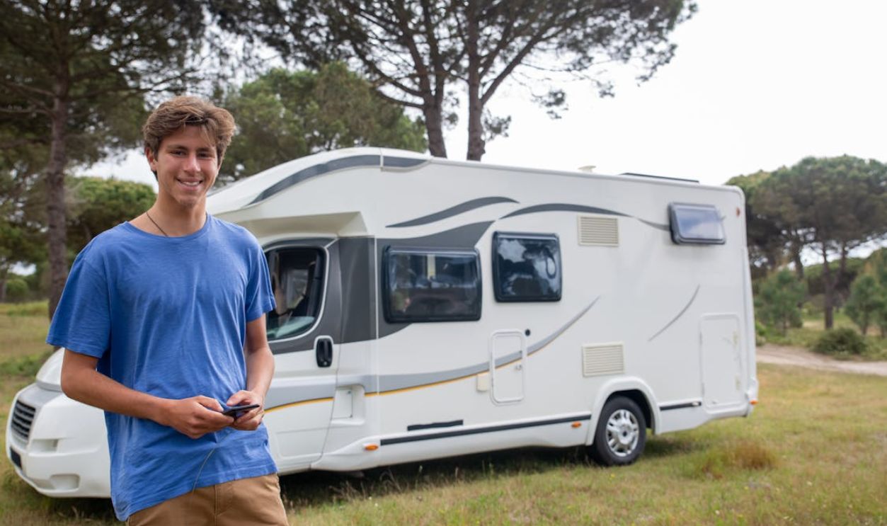 Man in Blue T-Shirt Standing by a White Camper Van