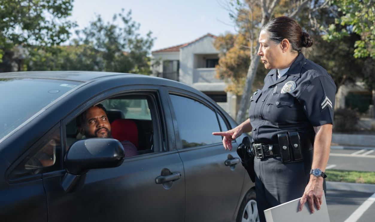 Policewoman Talking to a Man Riding in a Car