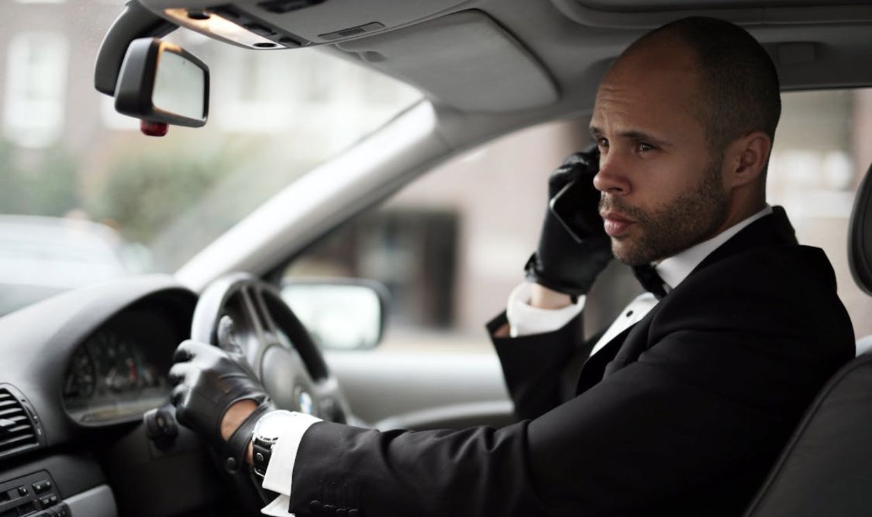 Man Driving Luxury Car While Talking on Phone