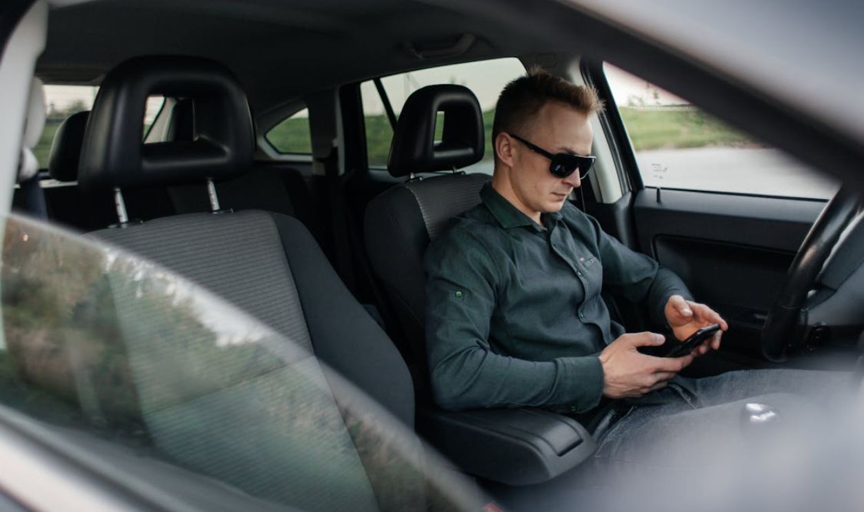 Man Sitting in a Car and Using Phone 