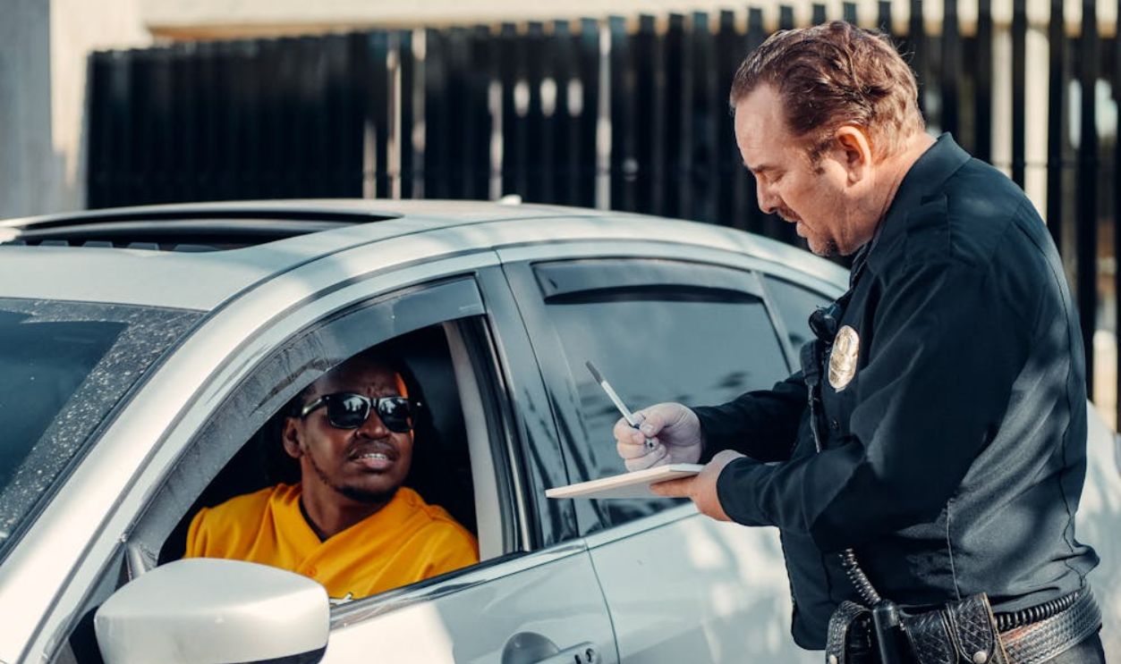 Man in Black Jacket Leaning on White Car