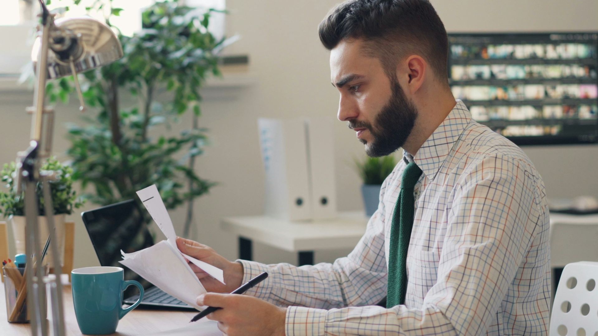 a man sitting at a desk with a laptop and papers