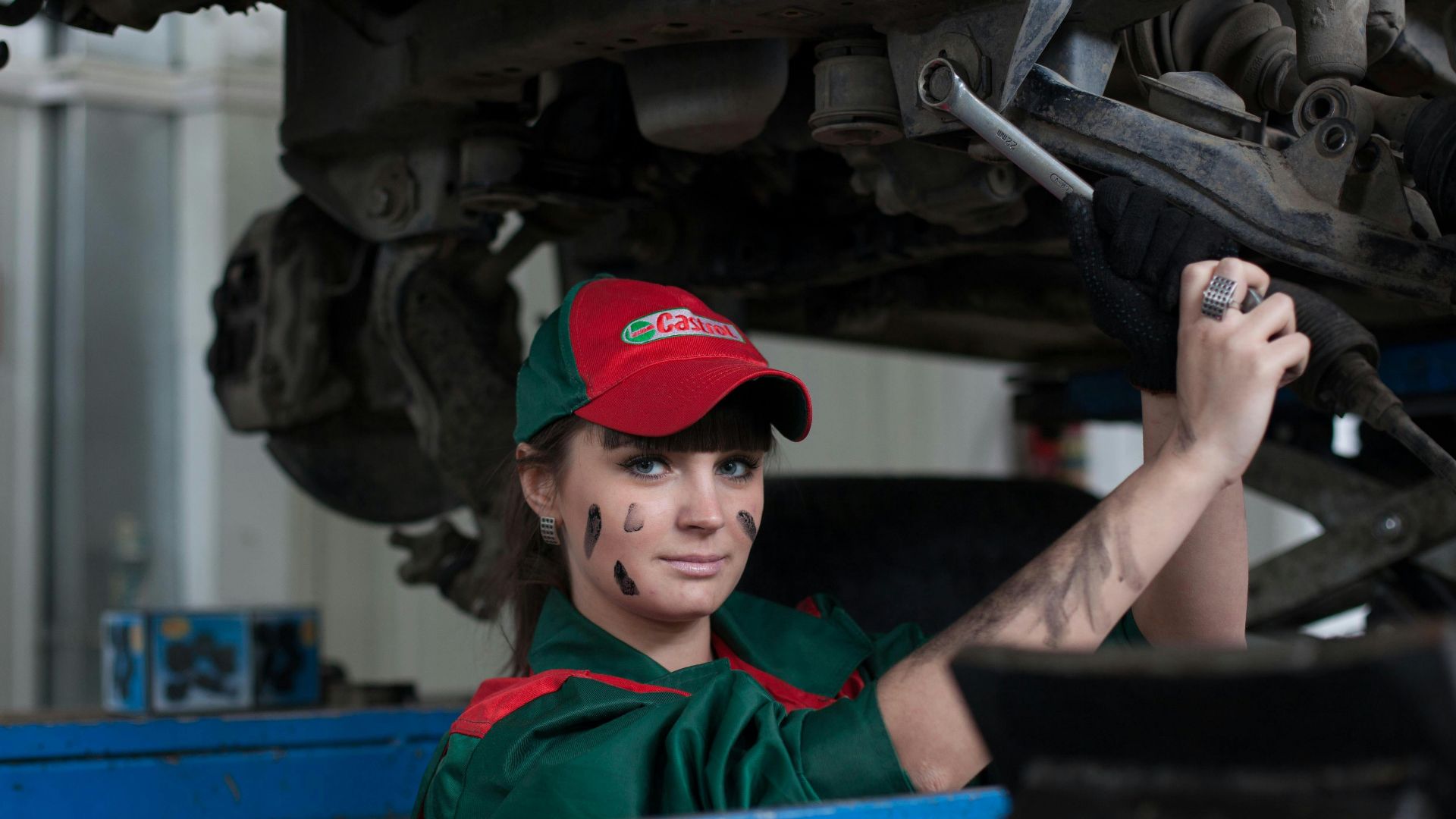 Female mechanic maintaining a car in an auto repair shop, showcasing skill and concentration.