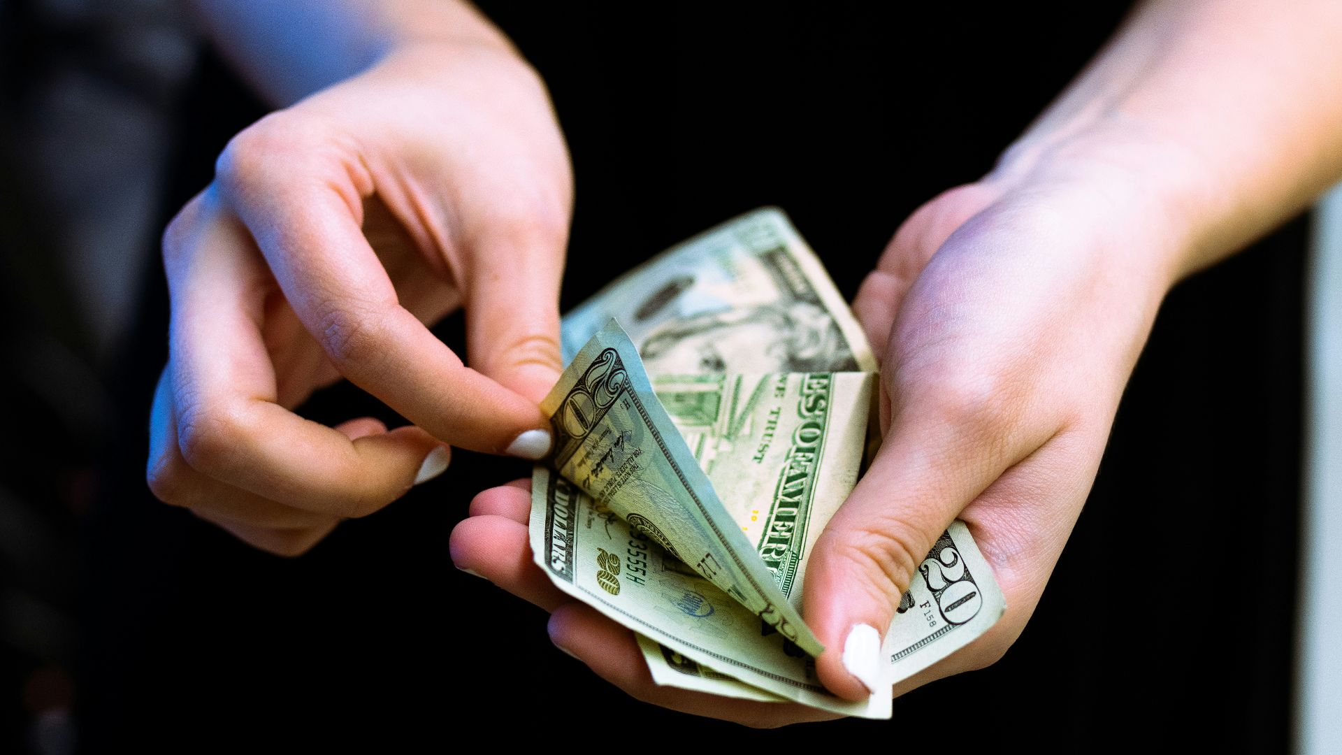 person holding fan of 100 us dollar bill