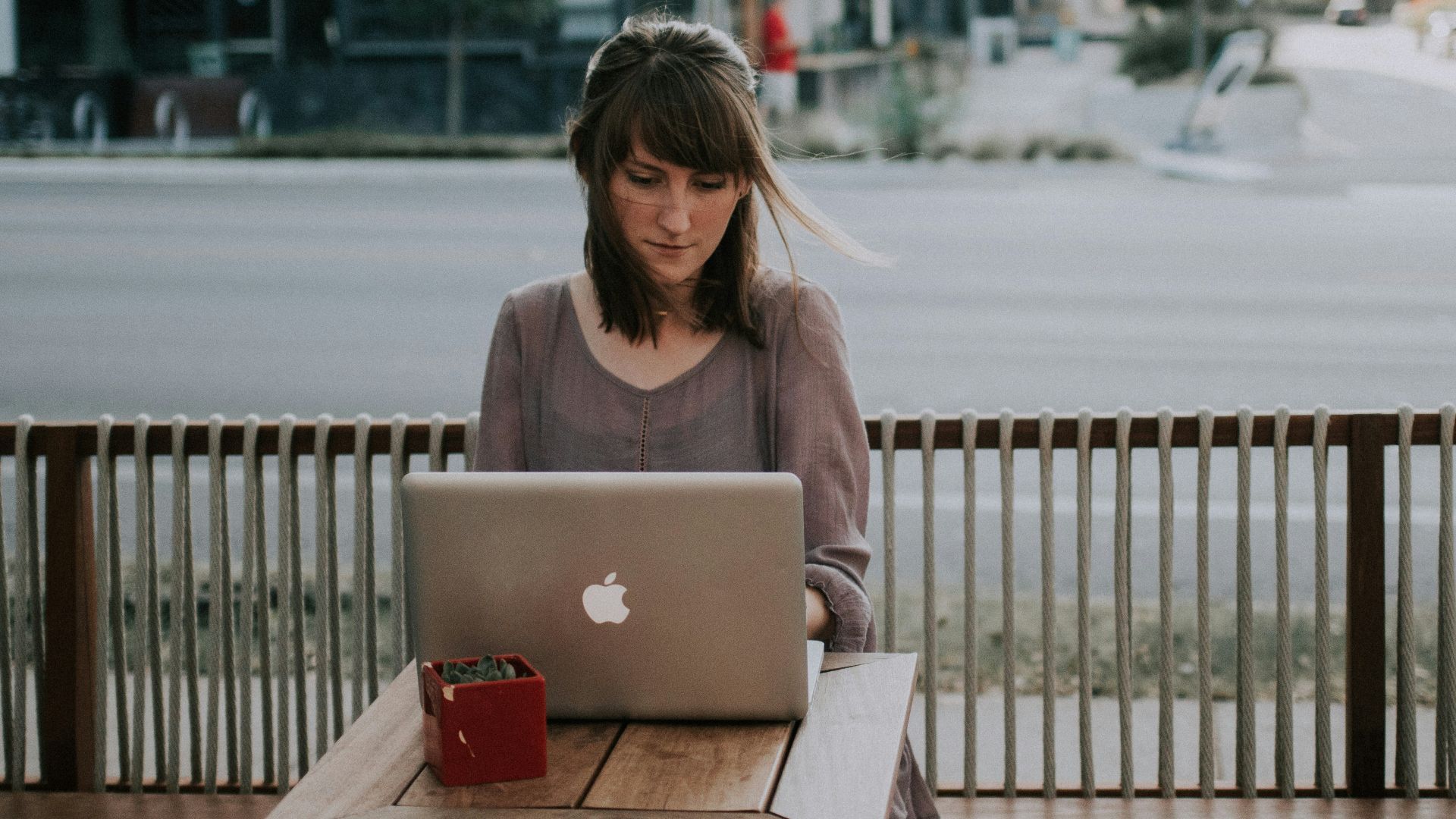 woman in gray shirt sitting on bench in front of MacBook
