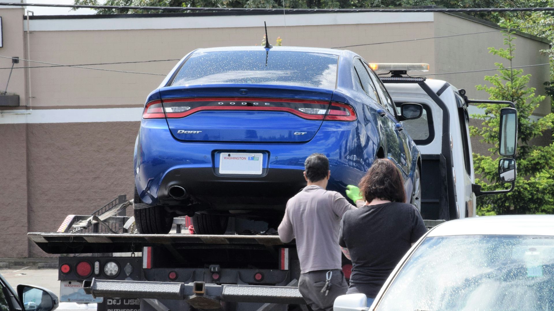 a blue car being loaded onto a flatbed truck