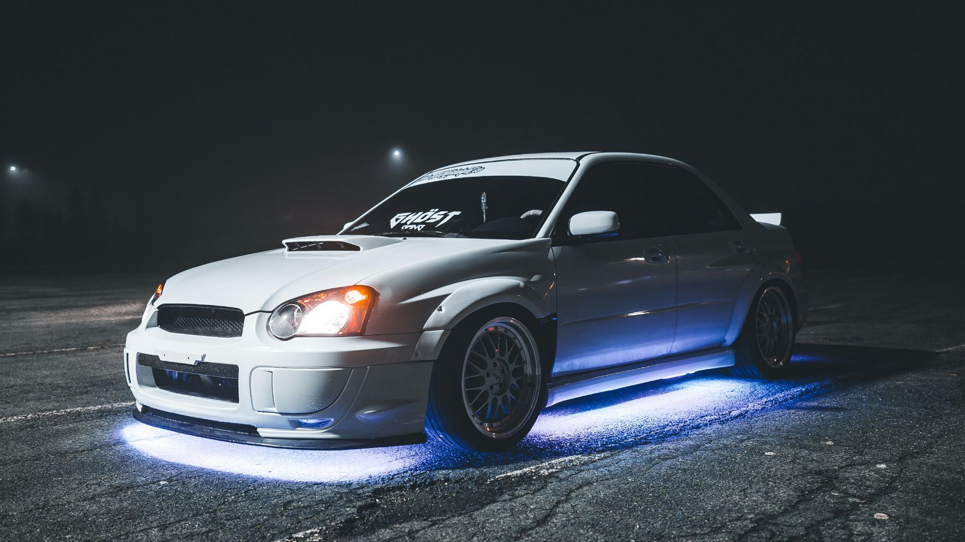 a white car parked in a parking lot at night