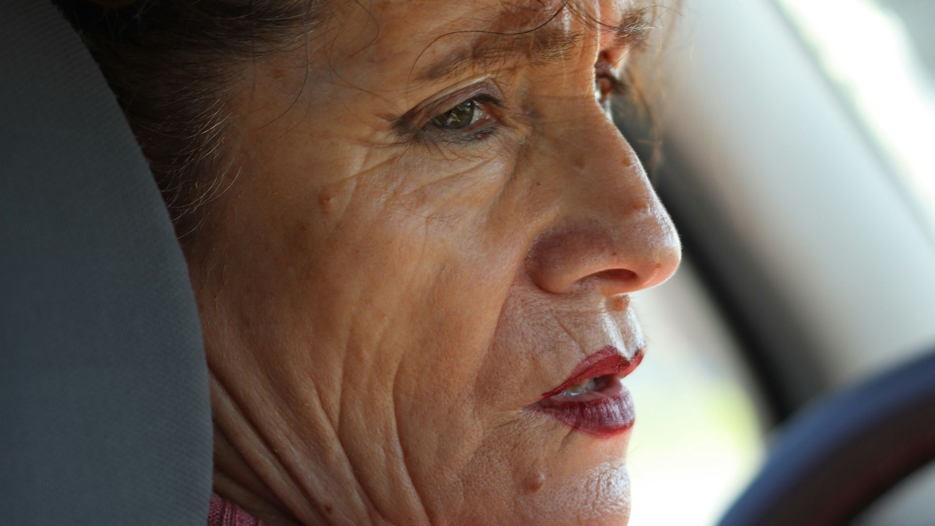 Woman appears worried while driving a car.