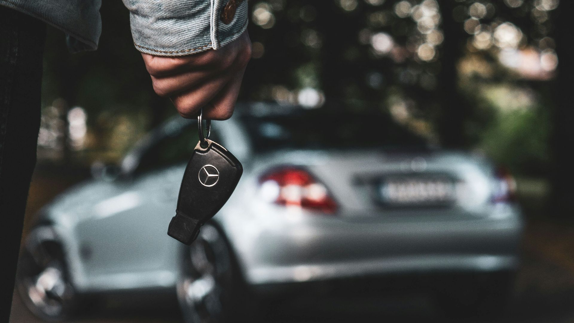 a person holding a car key next to a silver car