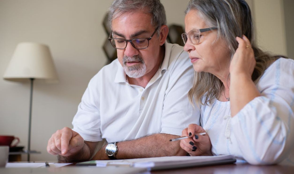 Elderly couple enjoying leisure time with crosswords at home, showcasing togetherness