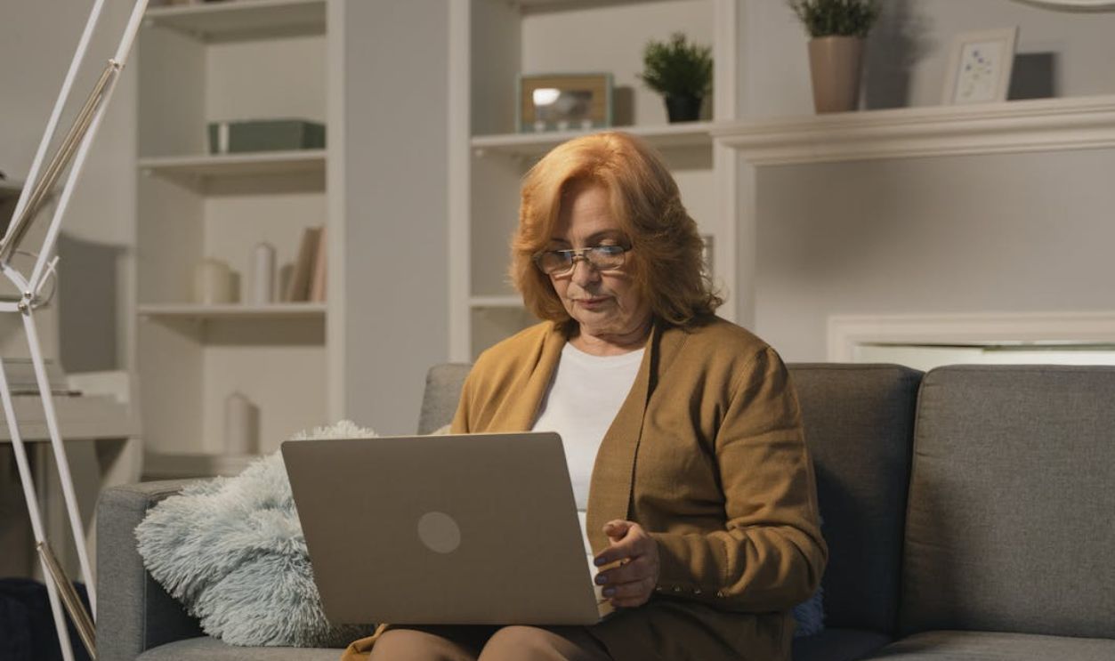 Senior woman with eyeglasses working on a laptop in a cozy living room setting