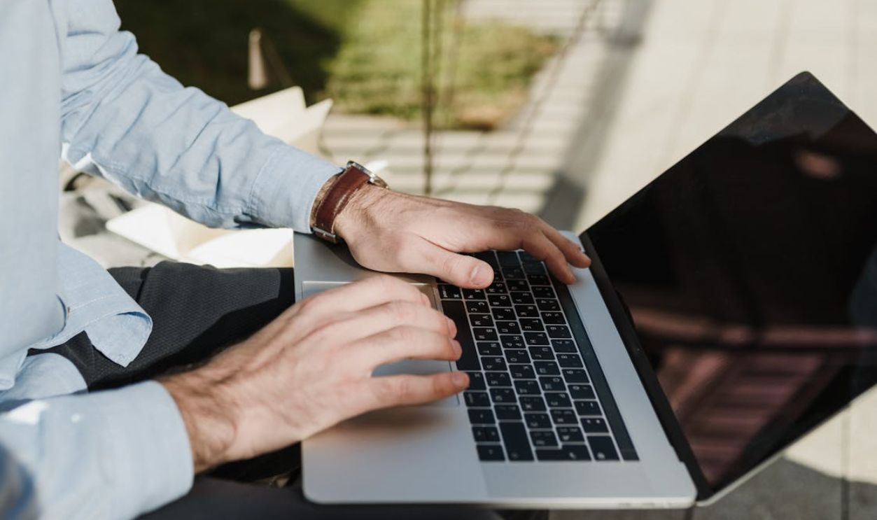 A man working on a laptop outdoors, exemplifying remote and flexible work environments