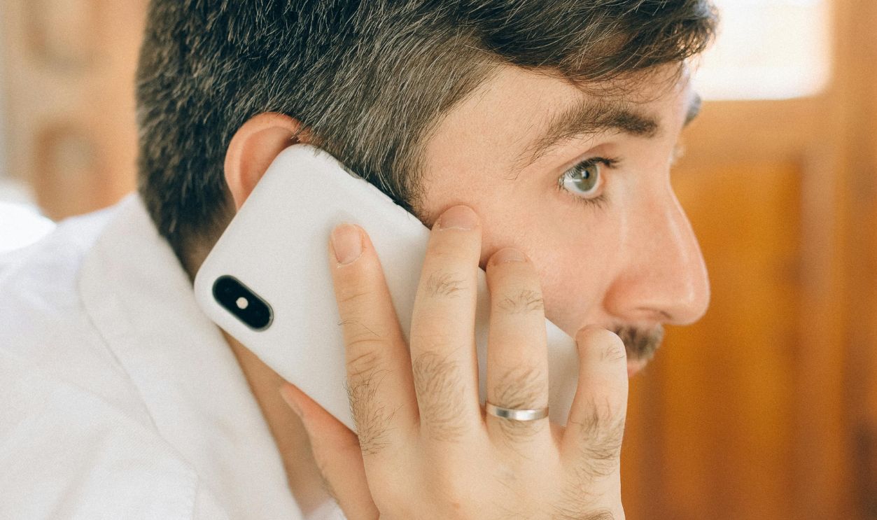 Side view of a caucasian man in white shirt talking on smartphone indoors