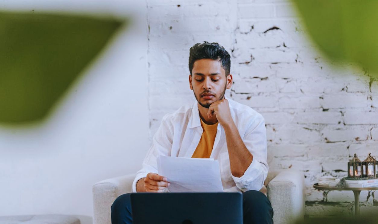 Man focused on reading a document while sitting indoors, reflecting concentration