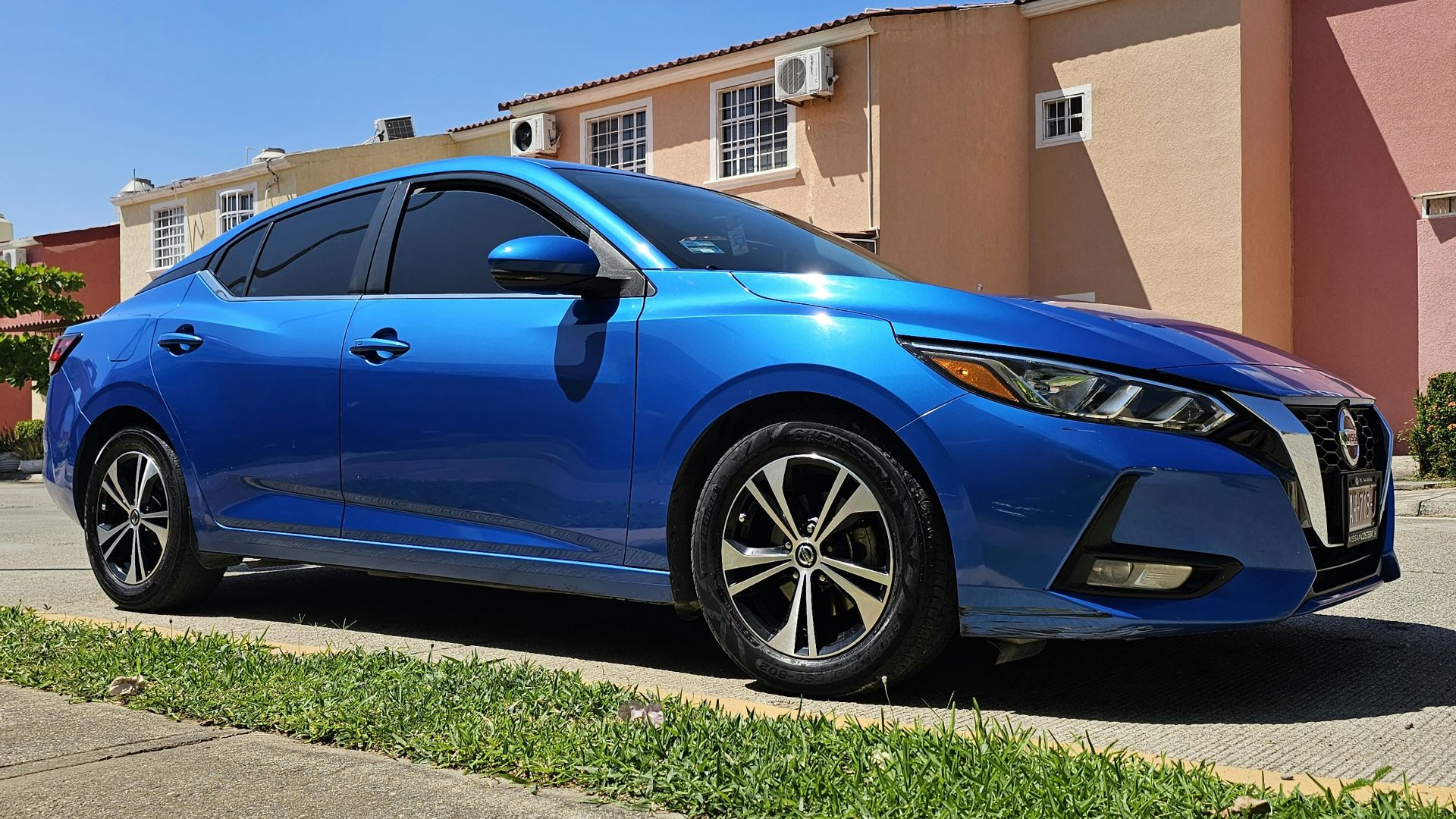 A blue sedan parked on a sunny street.