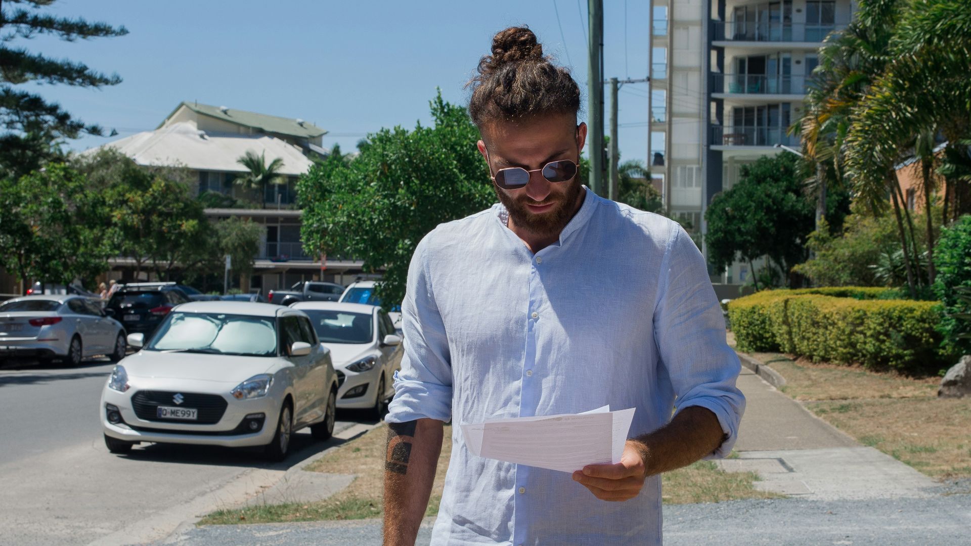 man in white button up t-shirt holding white printer paper