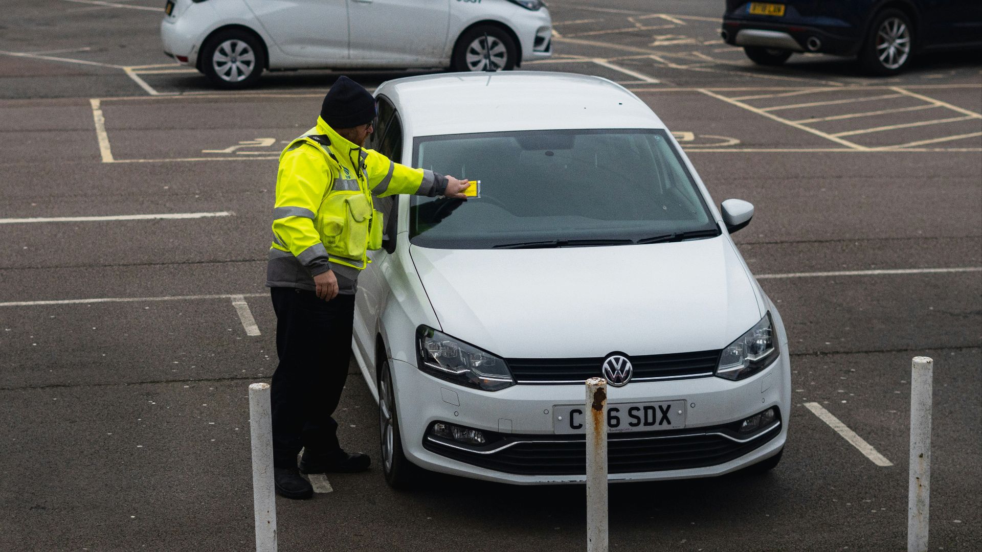 man in yellow jacket standing beside white car